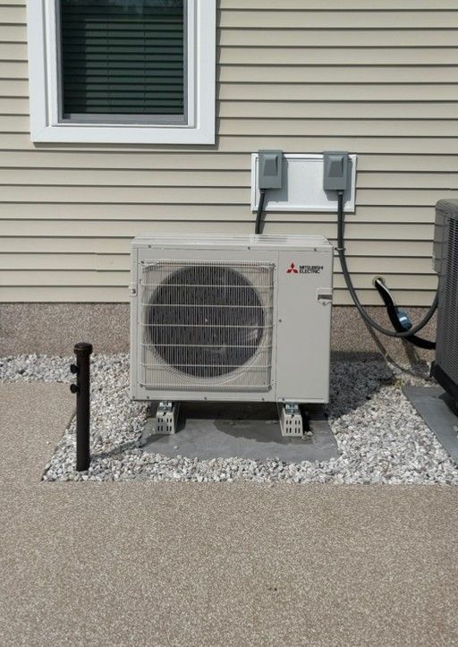 Outdoor Mitsubishi air conditioner unit beside a house with beige siding and gravel base.