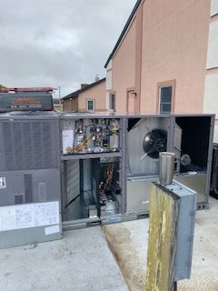 Open electrical units beside a building, with exposed wiring and a large fan housing.