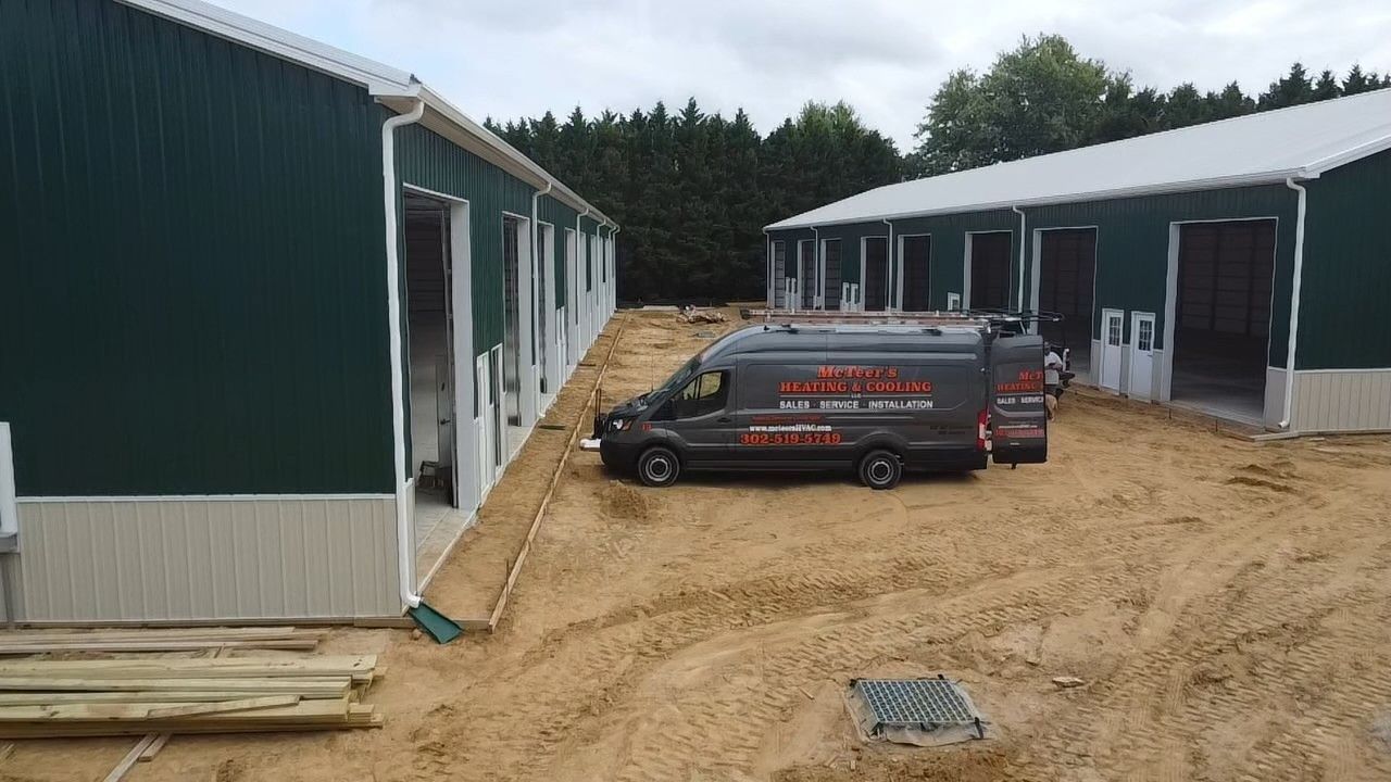 Construction site with two green buildings and a black car parked on a dirt path