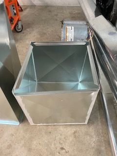 Empty metal utility bin on a concrete floor beside industrial equipment and rails