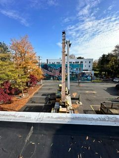 Rooftop view of a parking lot, white building, and autumn trees under a blue sky.