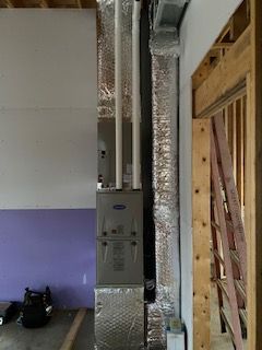 Basement utility area with HVAC equipment, foil ductwork, and unfinished wall framing
