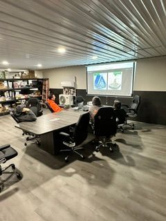 Conference room with people seated around a table watching a presentation on a screen