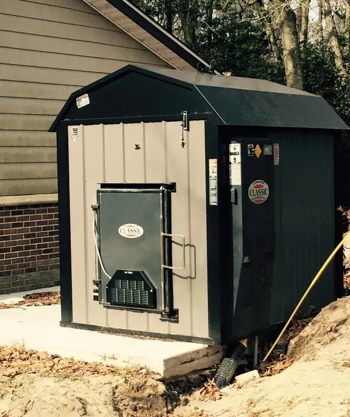 Small black and beige outdoor utility shed with a metal door beside a house