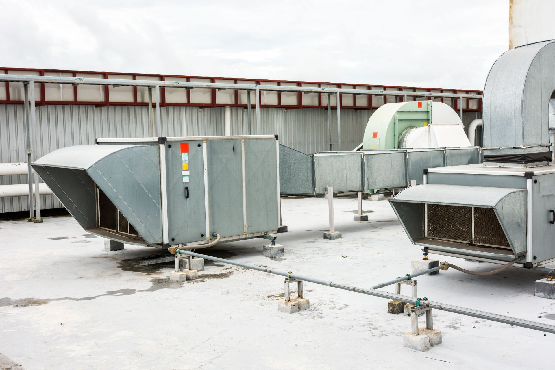 Rooftop HVAC units and ductwork on a flat industrial roof under overcast light