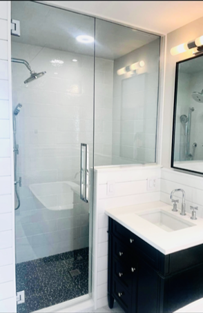 Modern bathroom with glass shower enclosure, white subway tile, black vanity, and mirror.