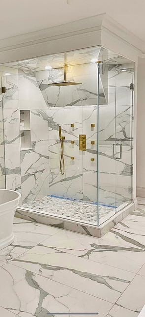 Luxurious marble shower with gold fixtures and glass doors.