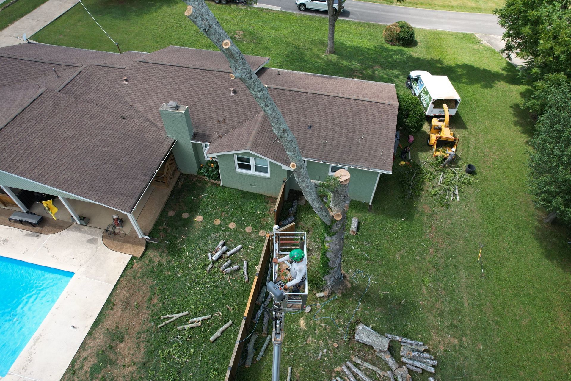An aerial view of a house with a pool and a tree being cut down.