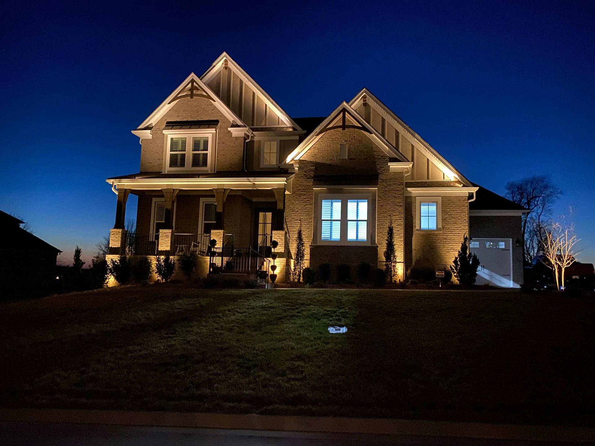 A house is lit up at night with a blue sky in the background.