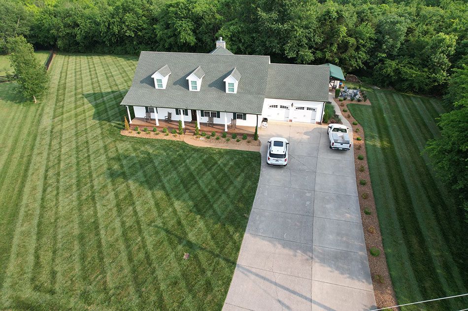 An aerial view of a house with two cars parked in front of it.