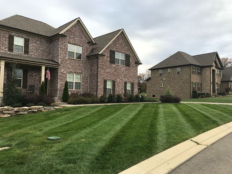 A brick house with a lush green lawn in front of it.