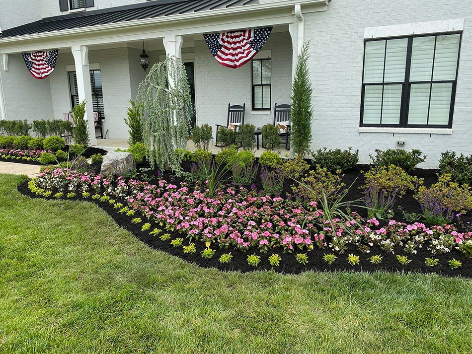 A white house with a lush green lawn and flowers in front of it.
