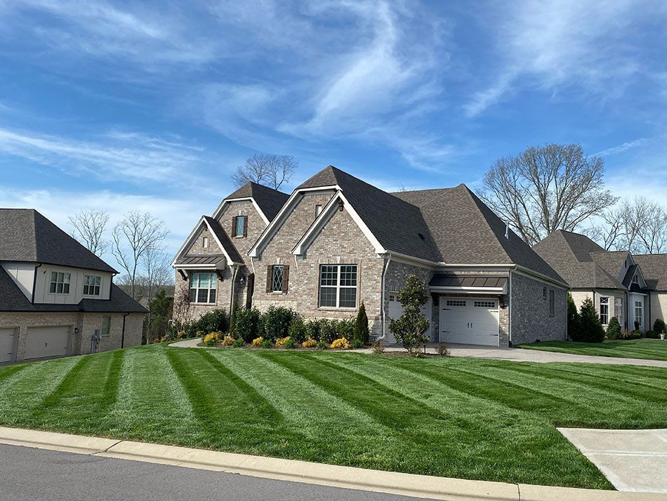 A large brick house with a lush green lawn in front of it.