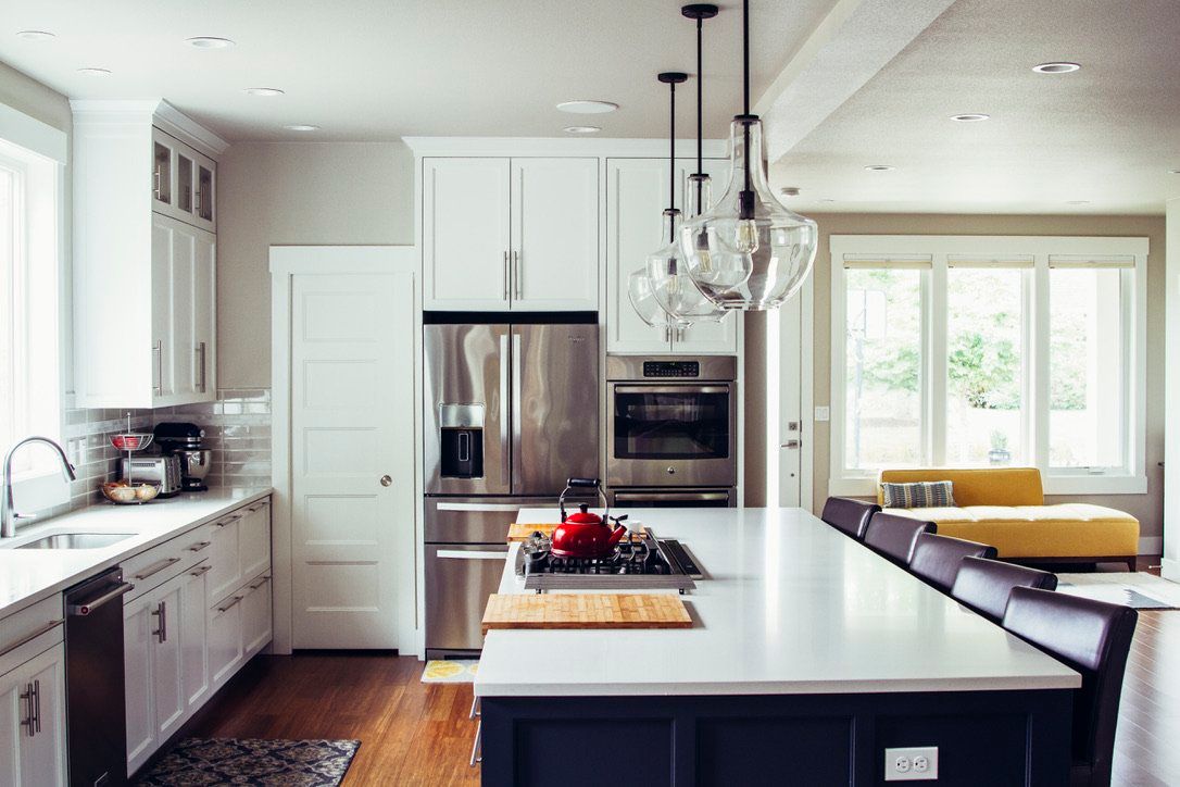 Bright modern kitchen with white cabinets, stainless fridge, island, and large window seat.