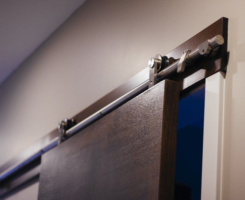 Close-up of a barn door hanging from a black metal sliding track on a wall