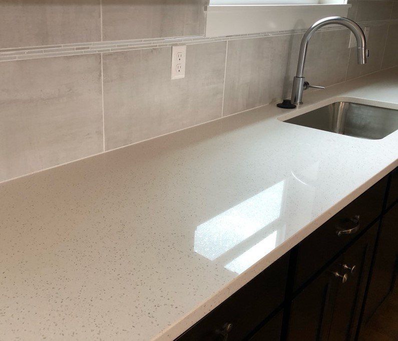Modern white kitchen countertop with a sink, faucet, and beige tile backsplash