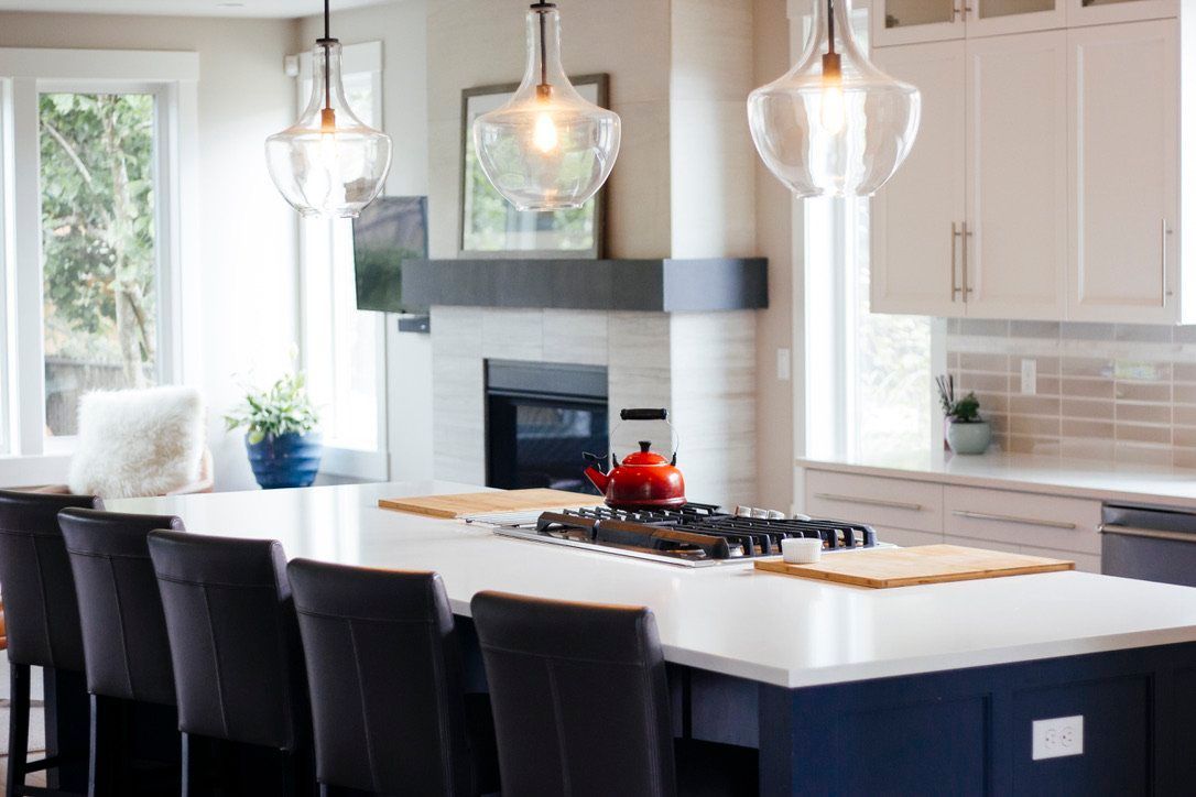 Modern kitchen with white cabinets, a large island, black bar stools, and glass pendant lights