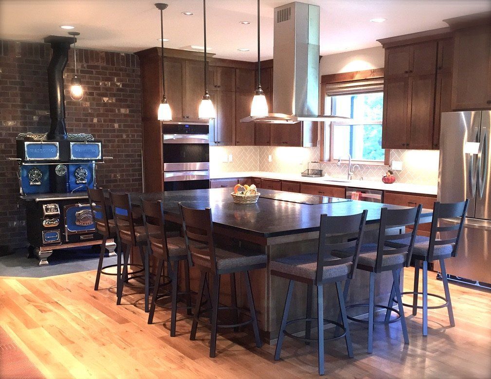 Modern kitchen with a large island, bar stools, pendant lights, and brick accent wall