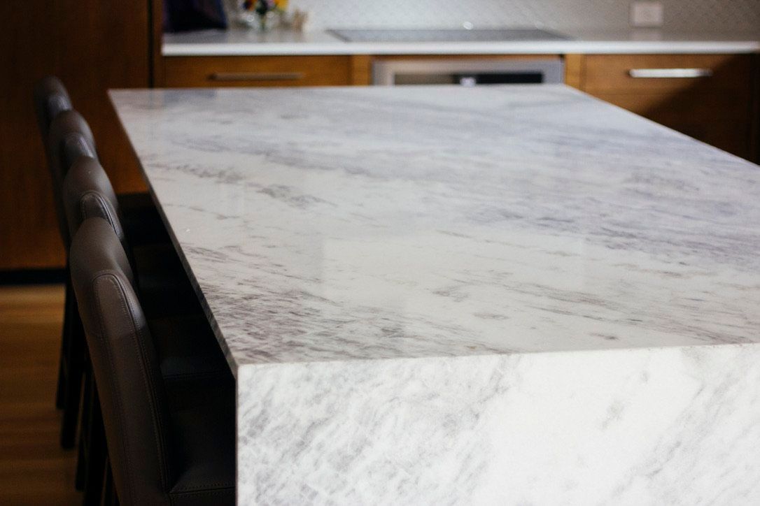 White marble kitchen island with dark chairs in a modern kitchen