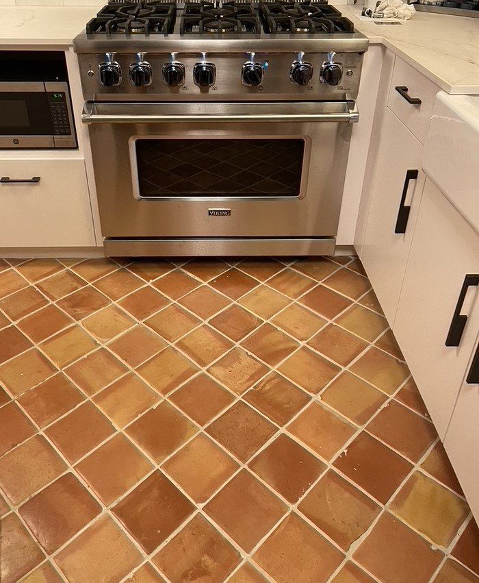 Kitchen with stainless steel oven and tan tiled floor between white cabinets.