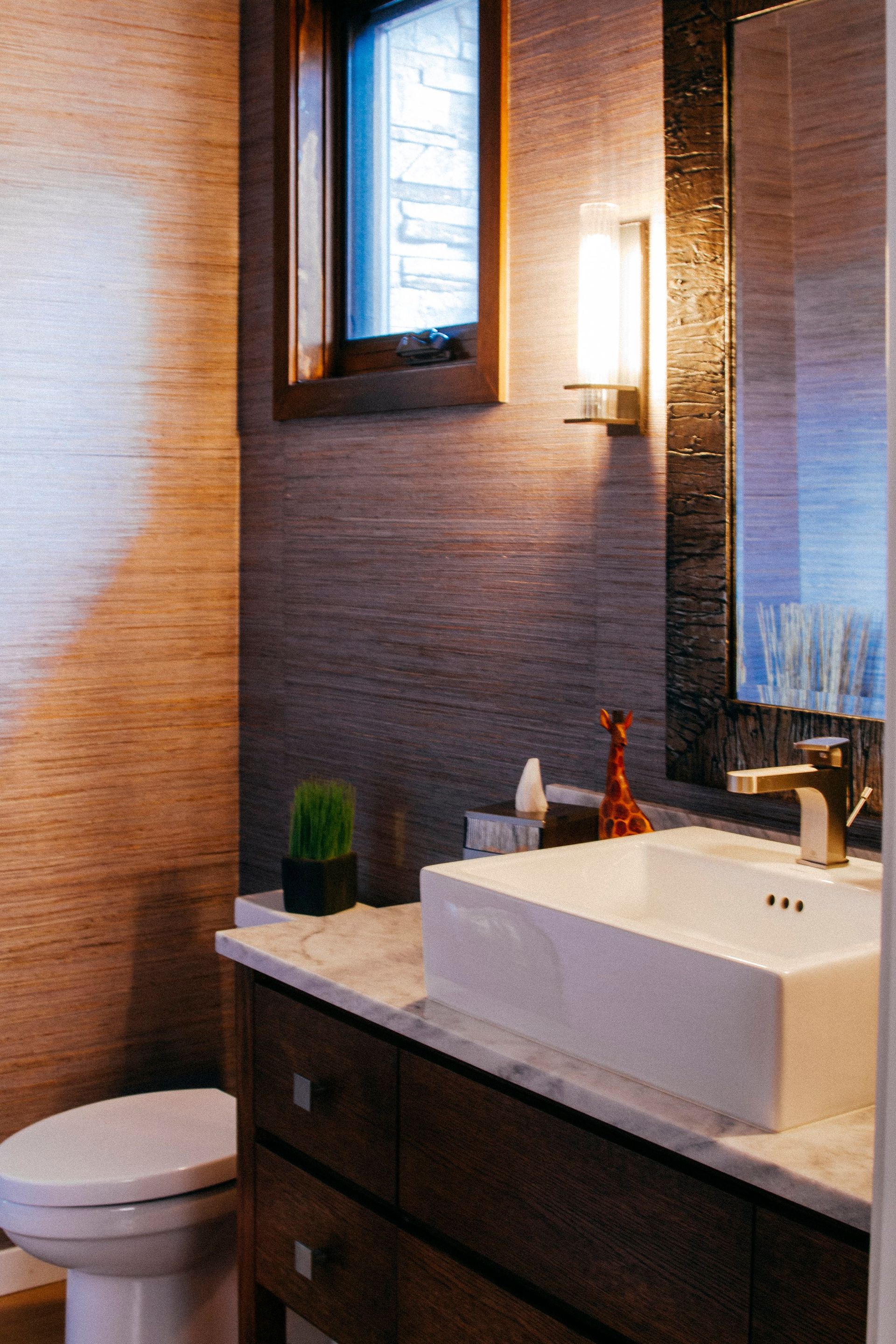 Modern bathroom with a toilet, vessel sink vanity, wall mirror, and warm lighting