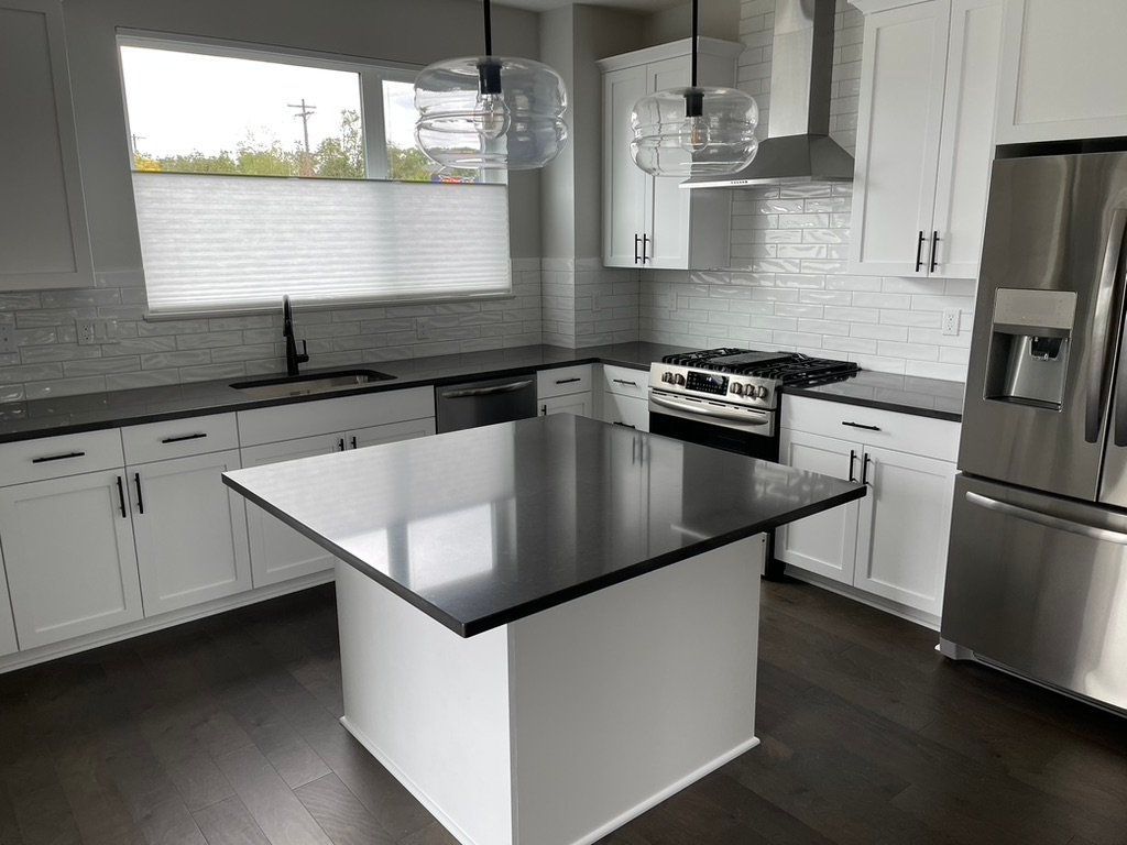 Modern kitchen with white cabinets, black countertops, stainless steel appliances, and a central island
