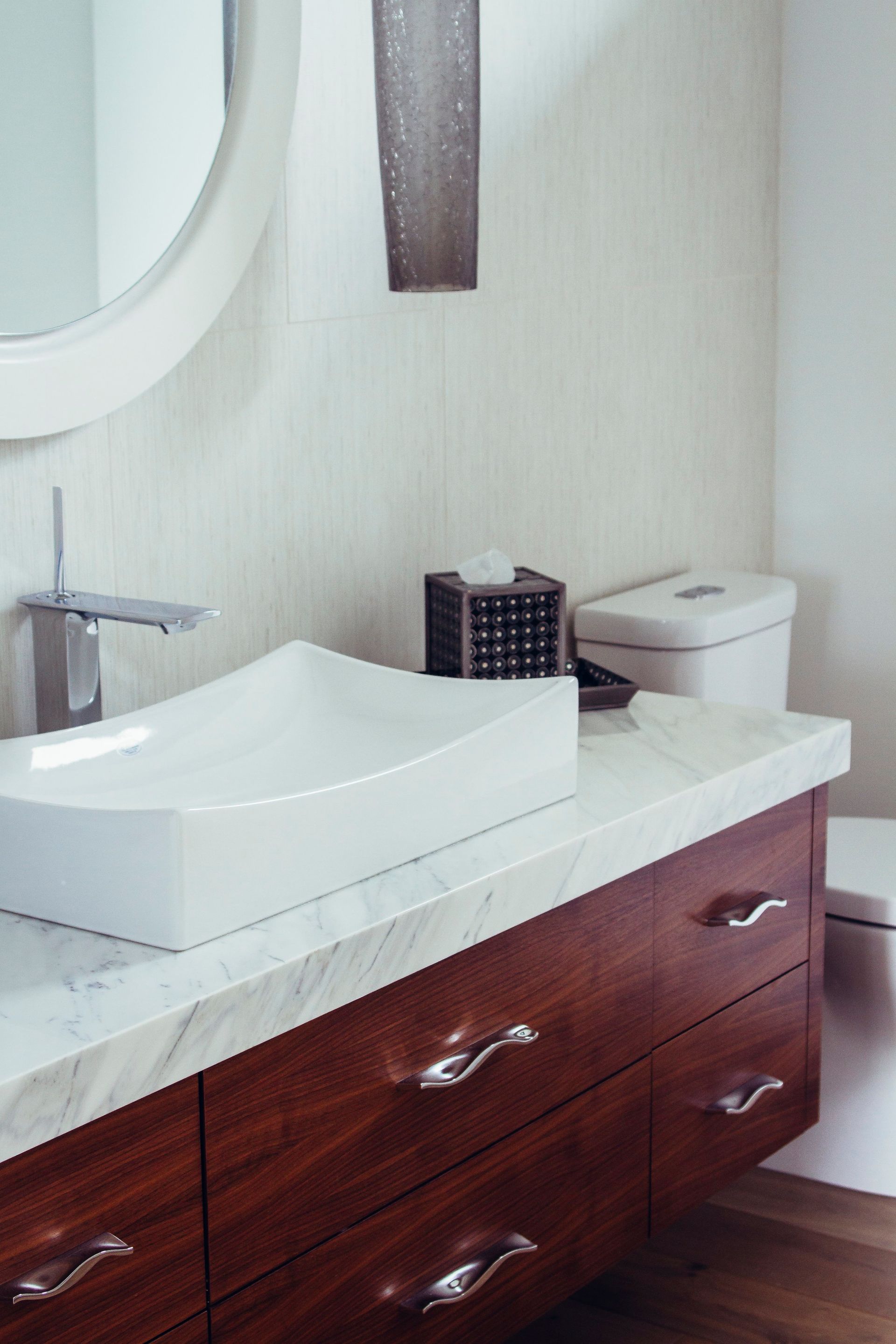 Modern bathroom vanity with vessel sink, faucet, mirror, and dark wood drawers
