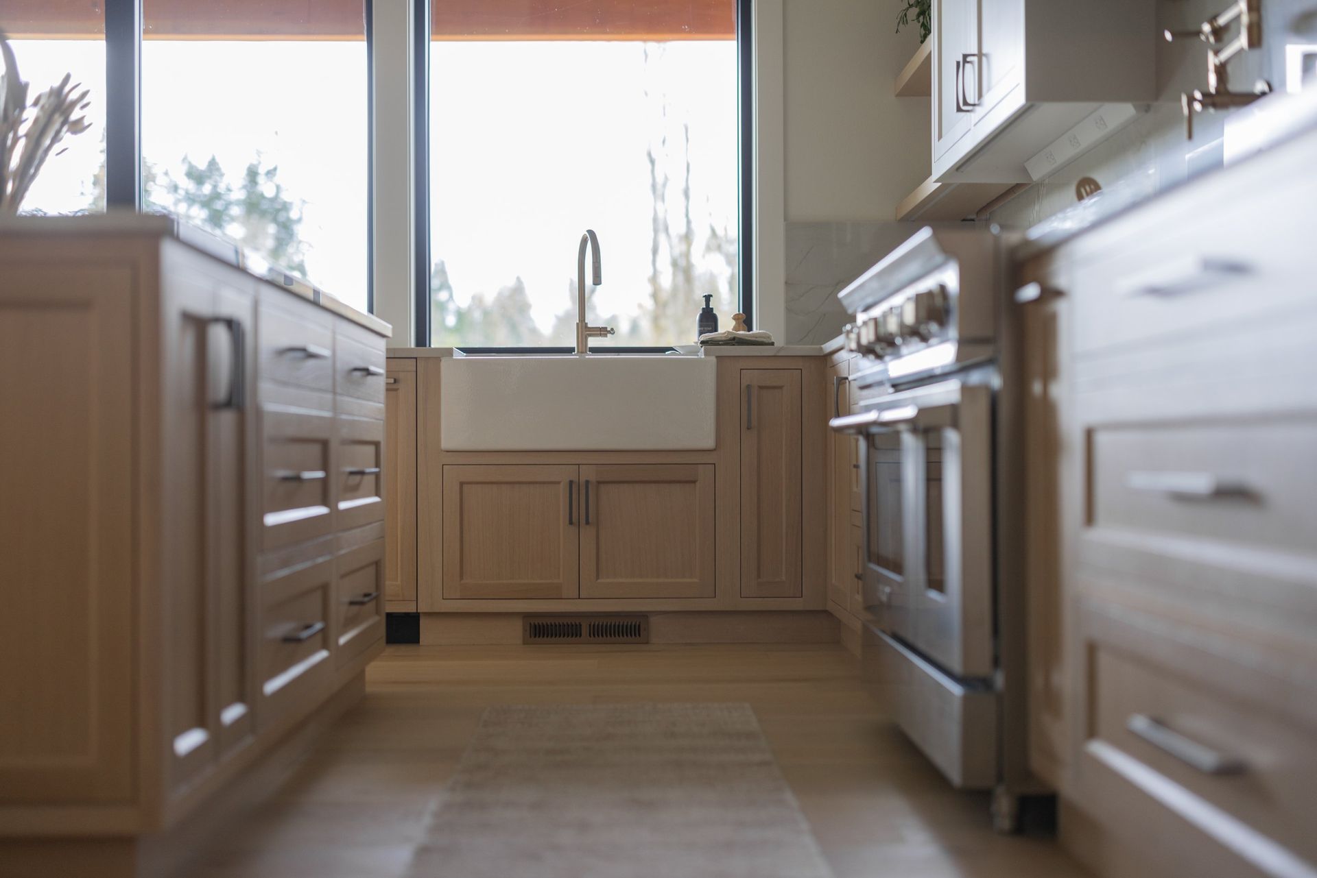 Bright kitchen with wooden cabinets, stove, and a large window above the sink.
