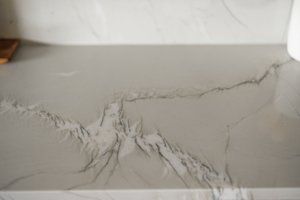 Cracked gray concrete floor with jagged fissures spreading across the surface