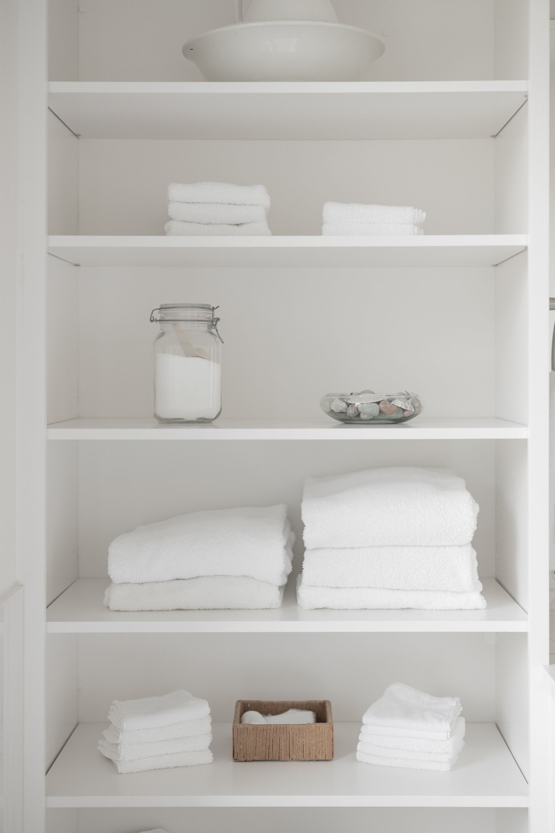 White bathroom shelf with neatly folded towels and small decorative items