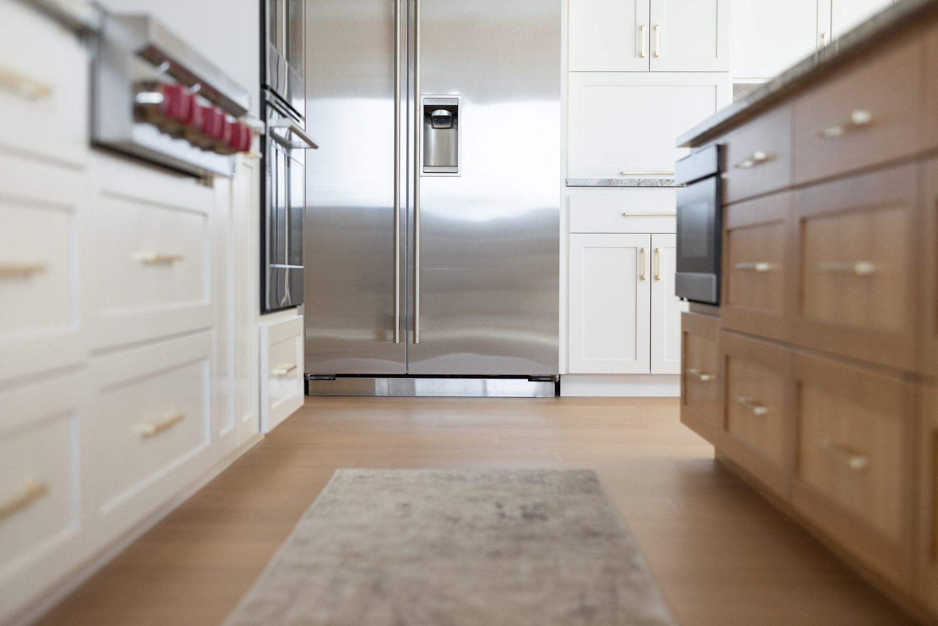 Modern kitchen with stainless steel refrigerator, white cabinets, and light wood island viewed from low angle