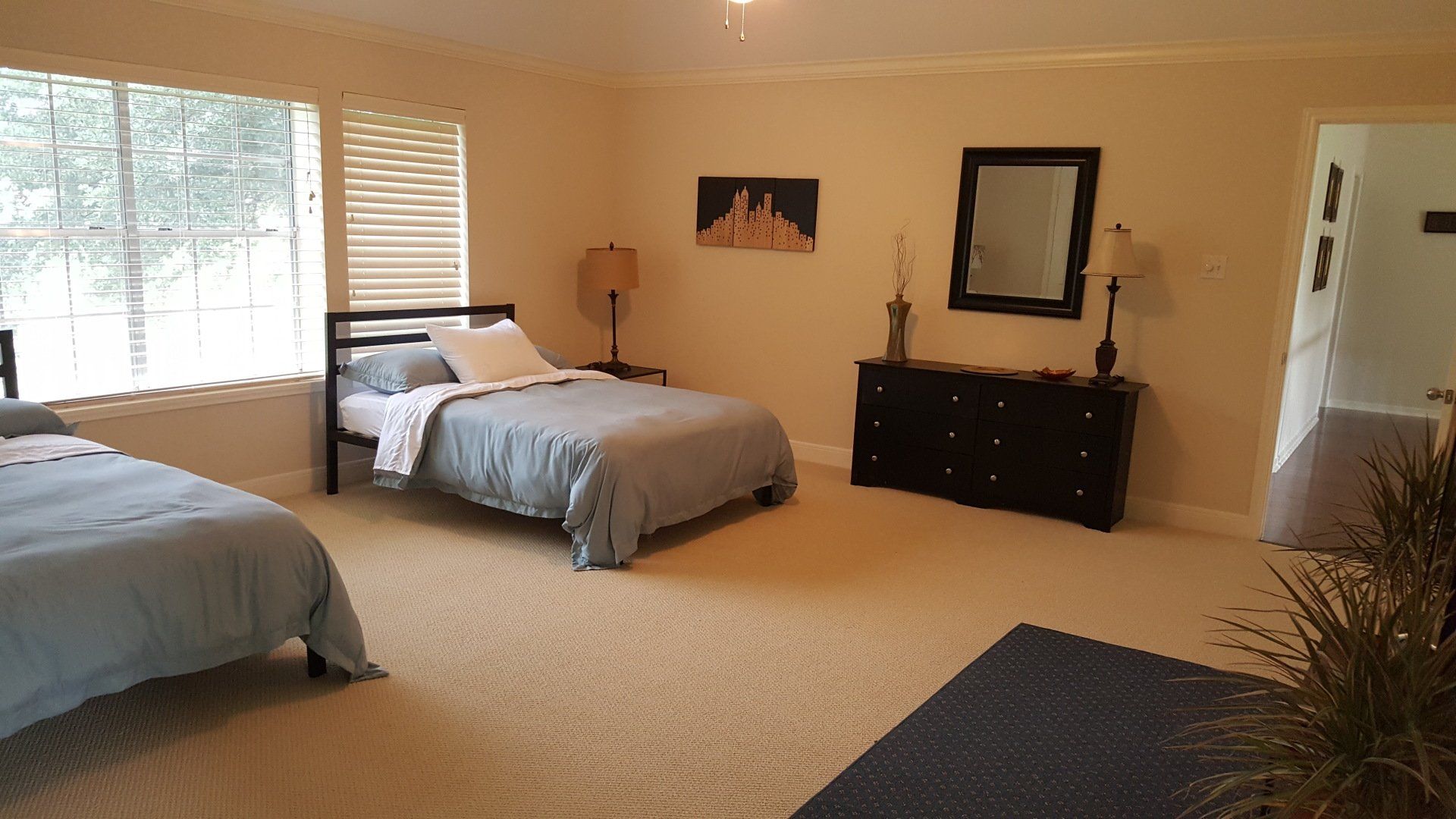A bedroom with two beds , a dresser and a mirror.