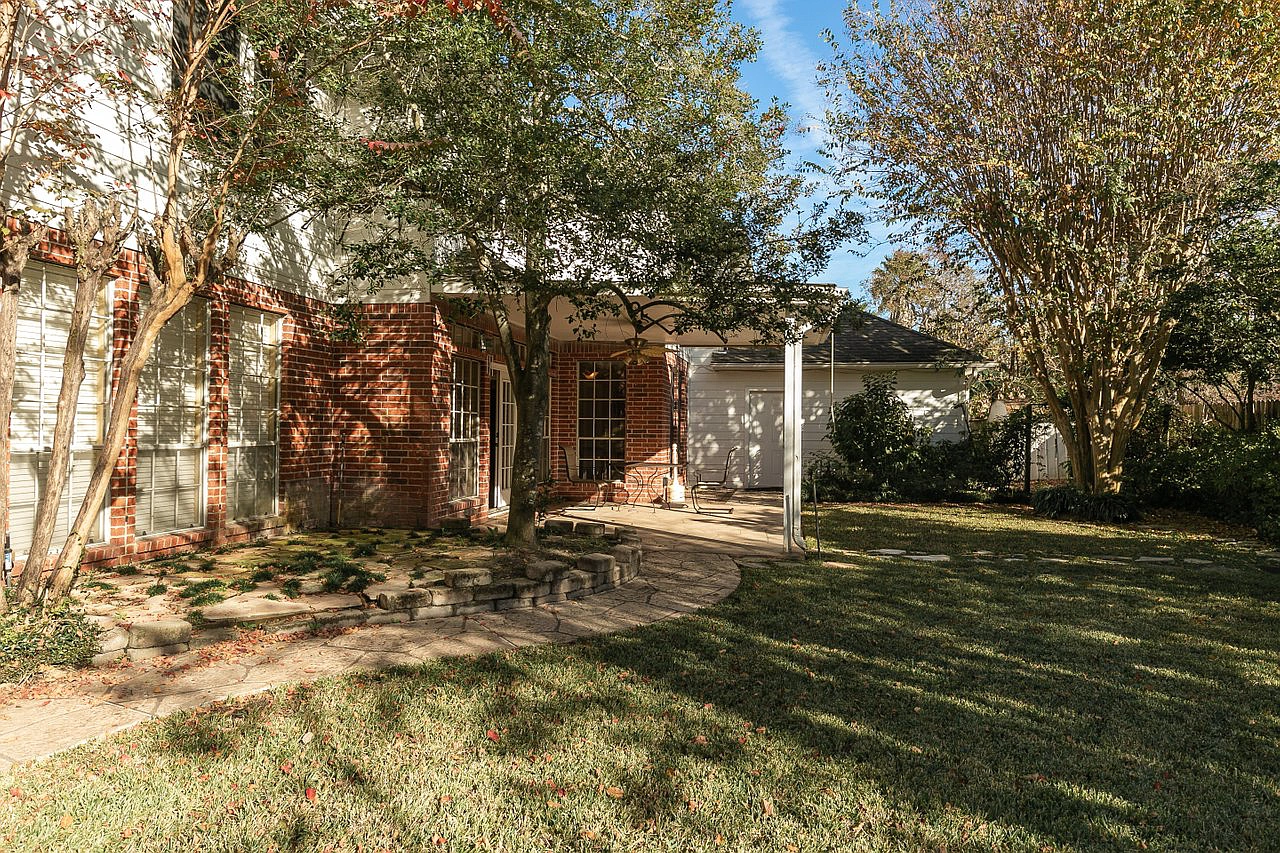 A house with a large lawn and trees in front of it.