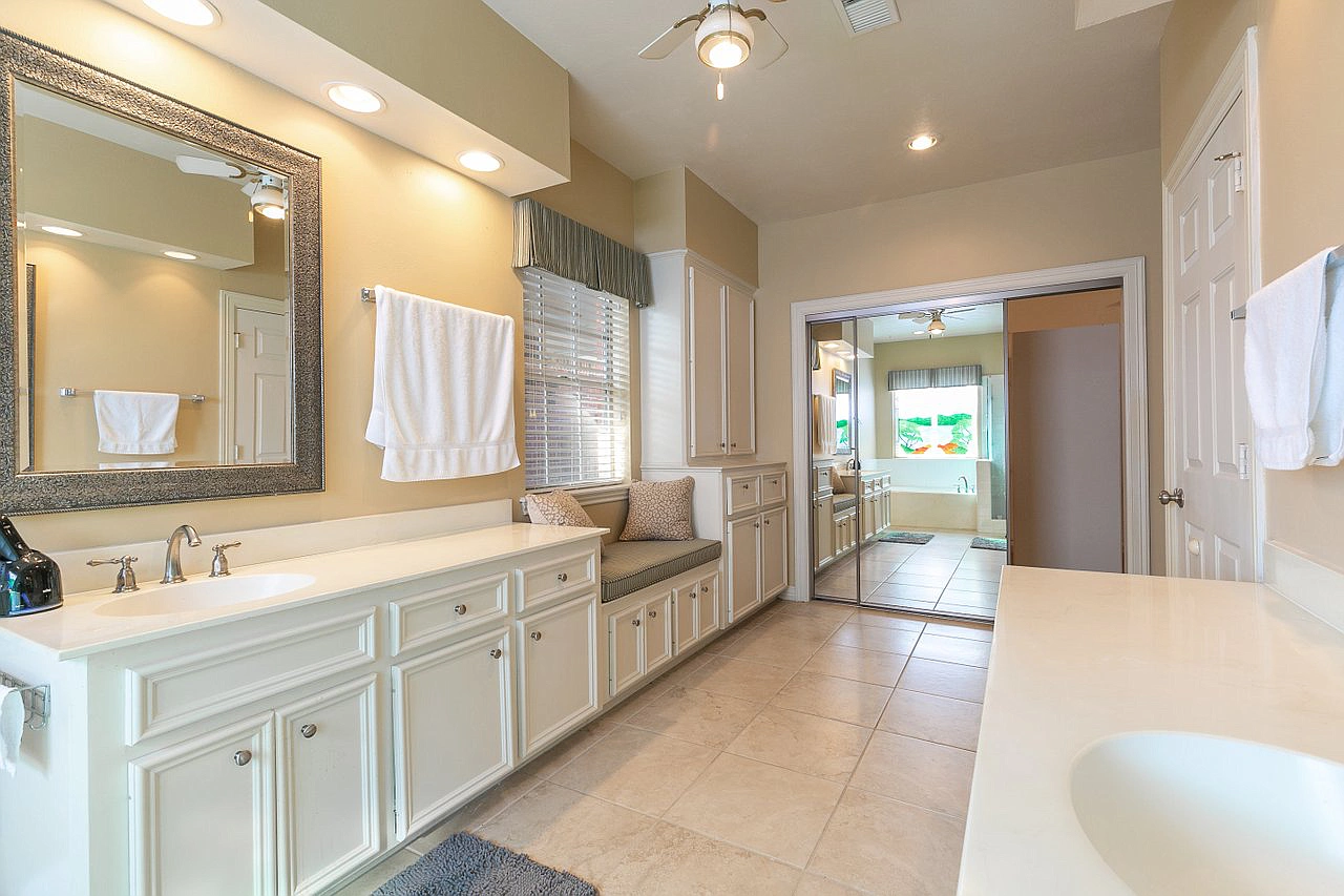 A bathroom with two sinks , a mirror and a ceiling fan.