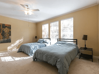 A bedroom with two beds and a ceiling fan.