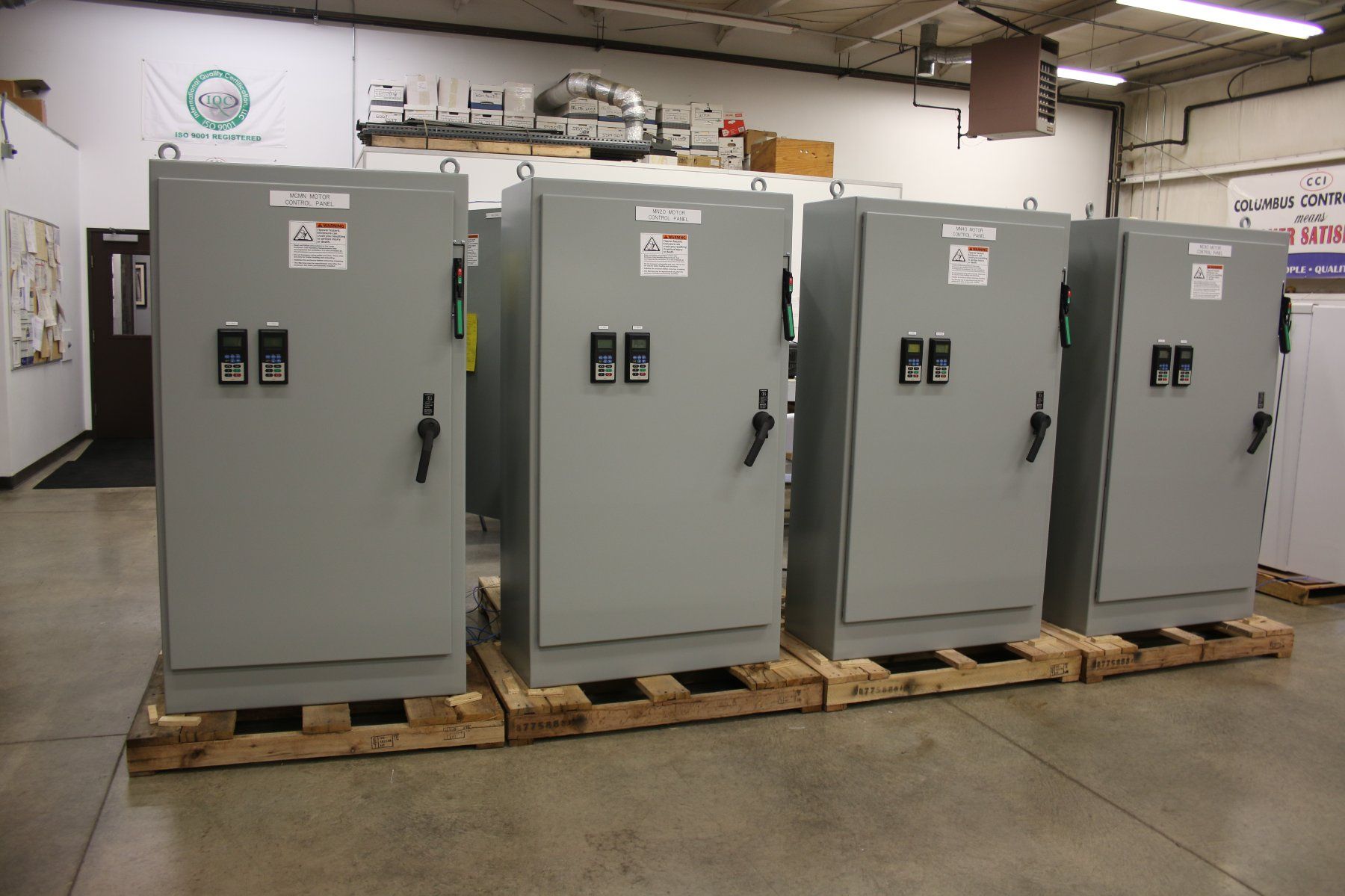 A row of electrical cabinets are sitting on wooden pallets in a room.
