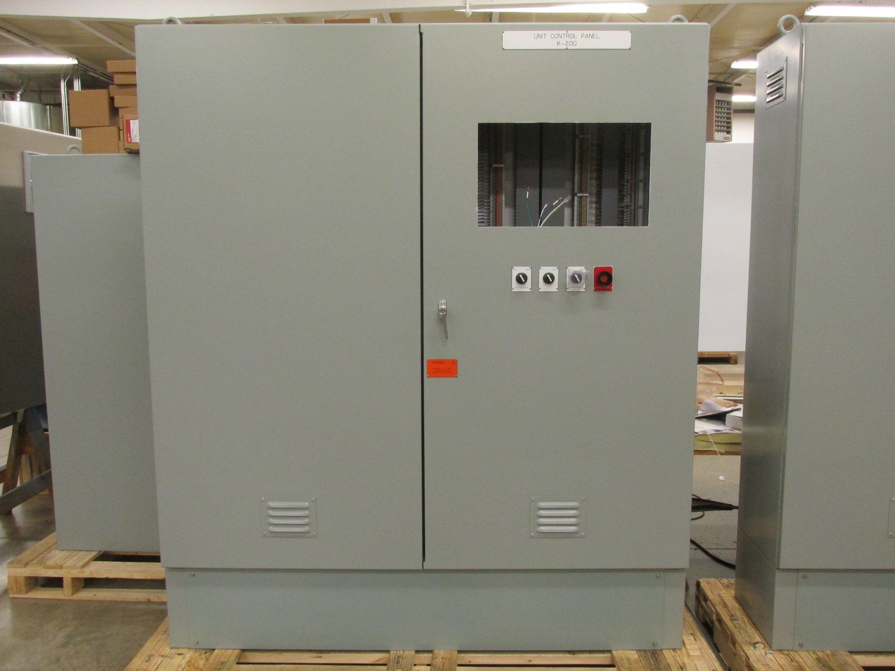 A gray cabinet with a window is sitting on a wooden pallet.