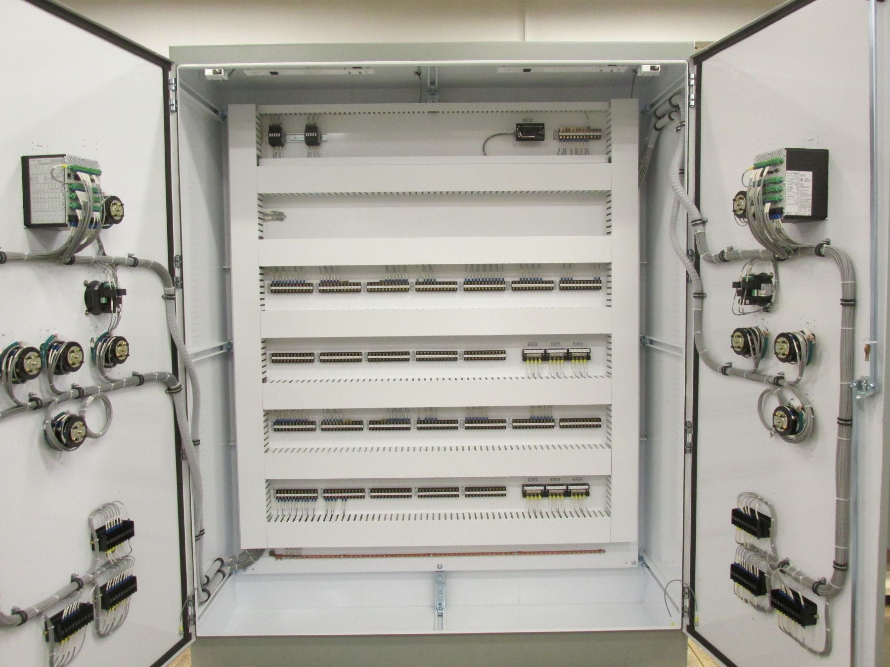 A large electrical box with the doors open and lots of wires coming out of it