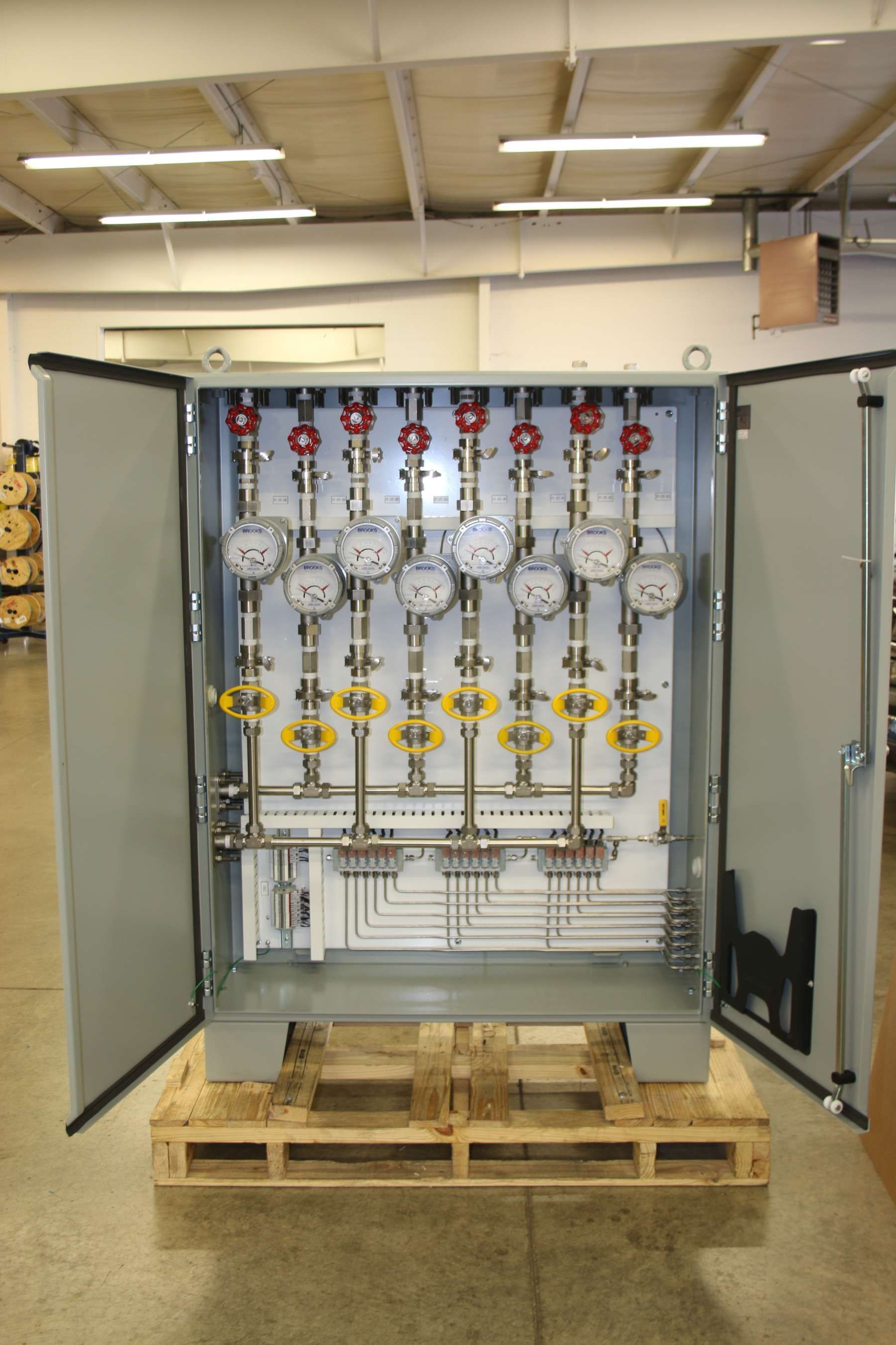 A cabinet with a bunch of gauges on it is sitting on a wooden pallet.