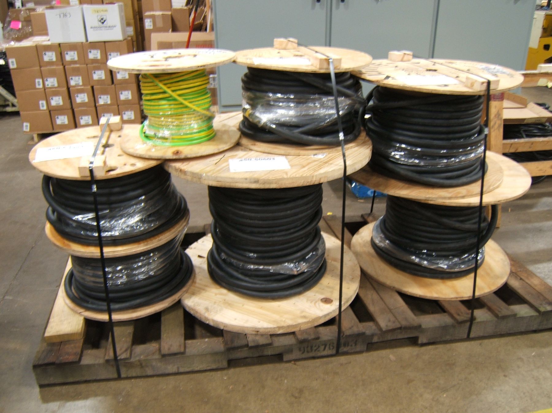 Several spools of wires are stacked on top of each other on a wooden pallet