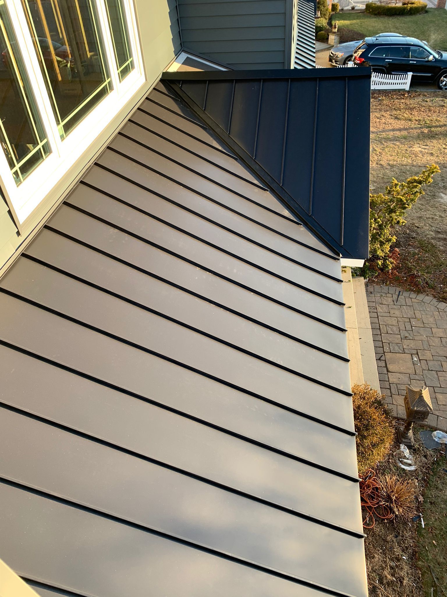 An angled view of a house roof featuring contrasting dark gray and light gray metal panel sections.