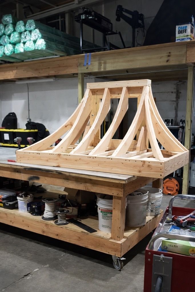 A custom wooden curved hood range frame sitting on a workshop workbench.