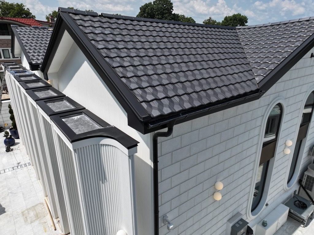 High-angle shot of a modern building with a dark tiled roof, white paneled walls, and arched windows.
