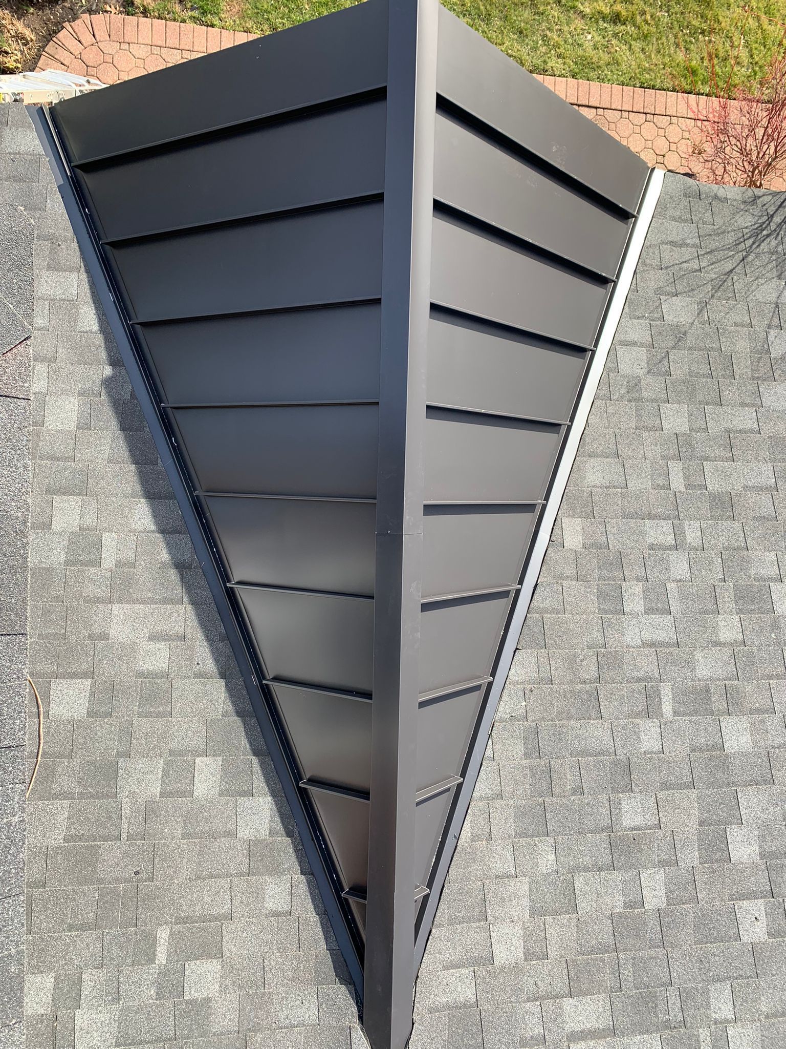 Dark gray metal siding on a triangular roof peak, with a shingled roof.