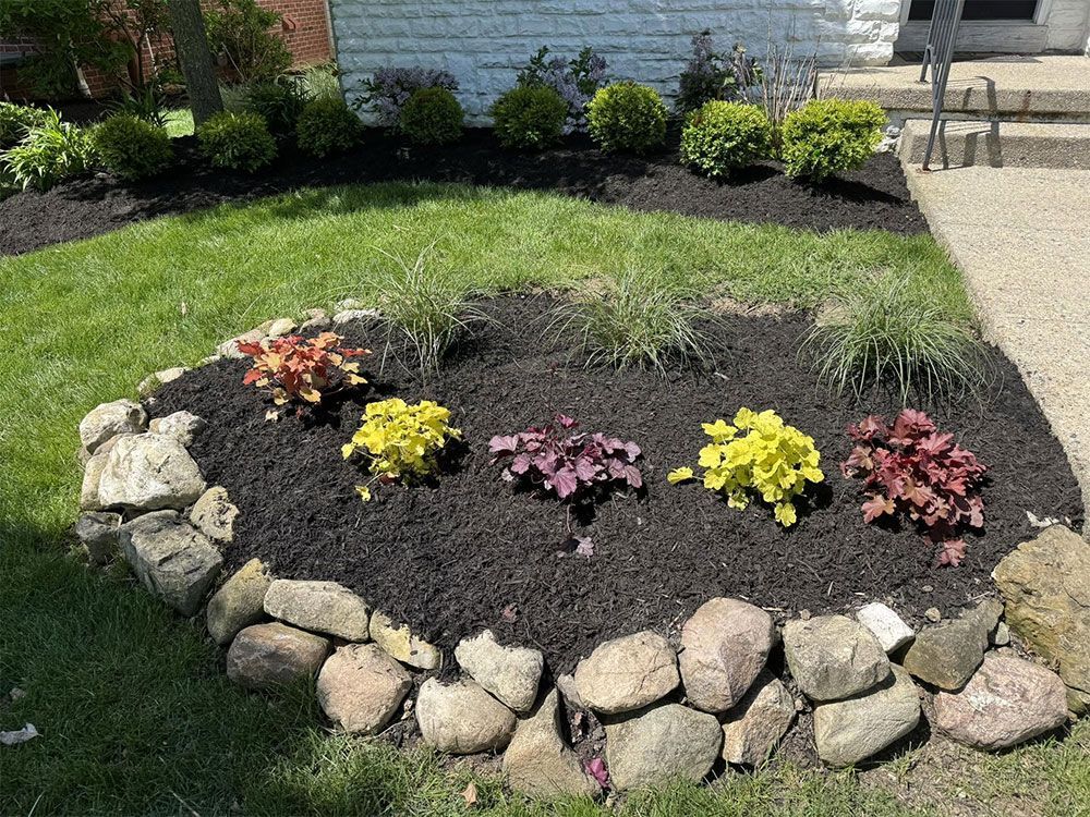 Rock-bordered flower bed with colorful small plants in a landscaped yard
