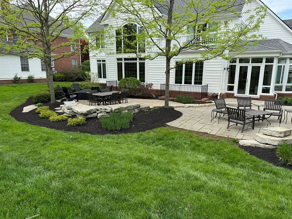 Backyard patio with outdoor dining sets, stone walkway, and white house with large windows