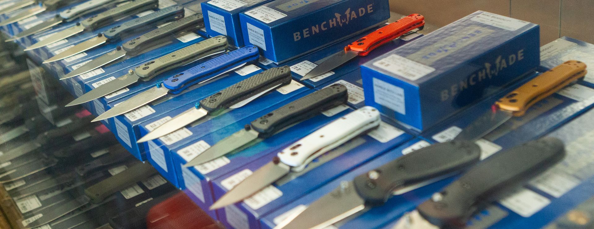 A display of Benchmade pocket knives, in their boxes. The knives have different colored handles, and the boxes are blue.