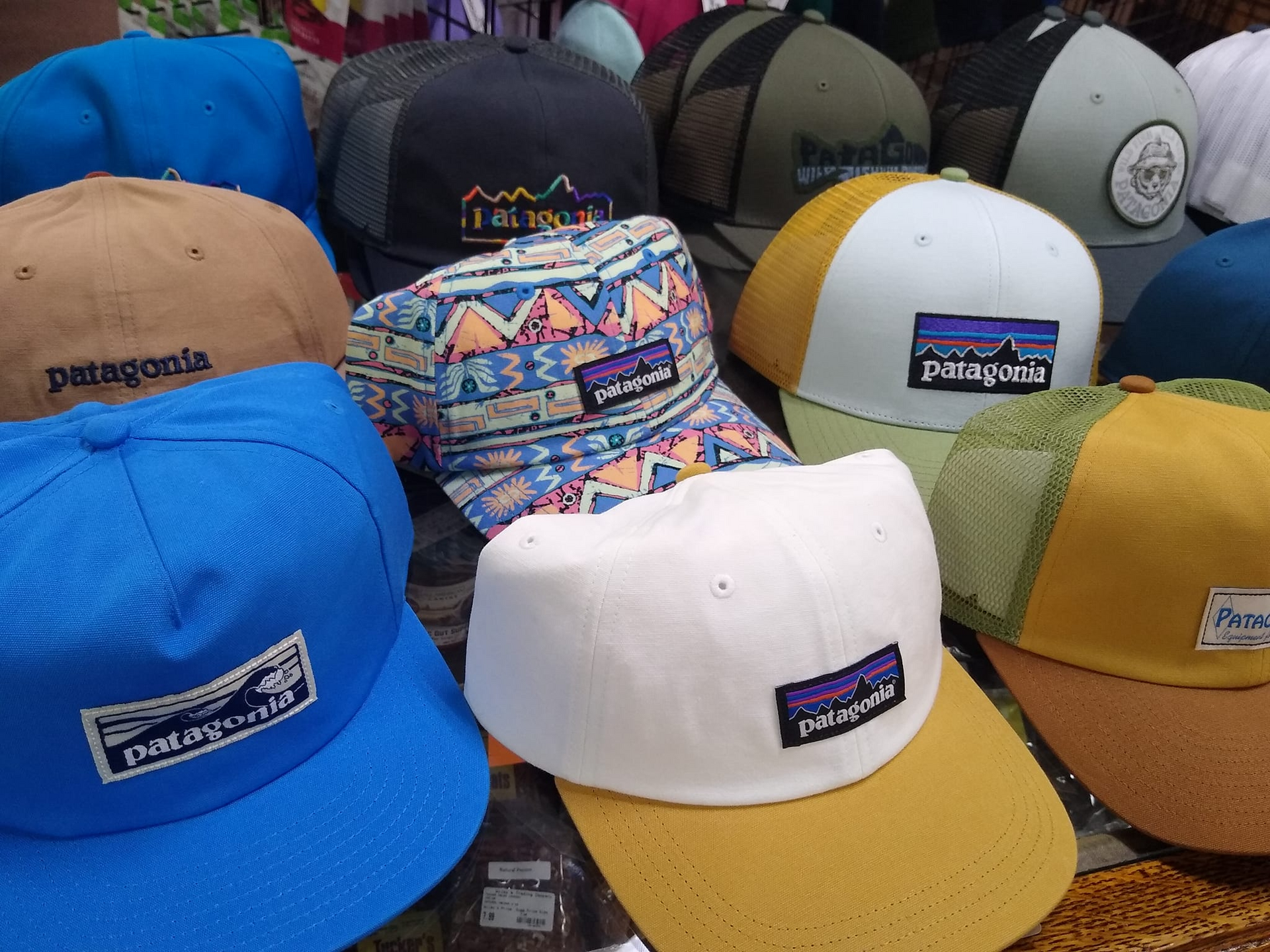 A close-up of a variety of Patagonia hats, including blue, white, tan, and patterned caps, all with the brand's logo.