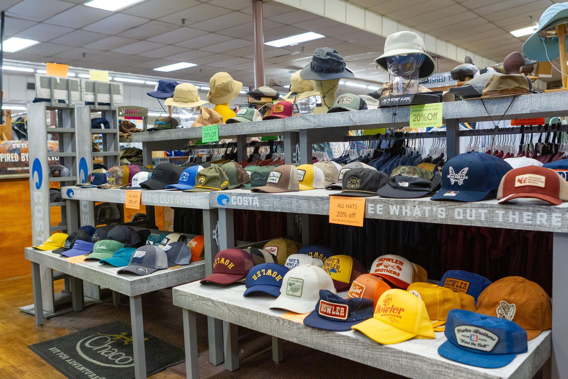 Display of various hats in a retail store. Baseball caps, bucket hats, and other styles are arranged on shelves and display stands.