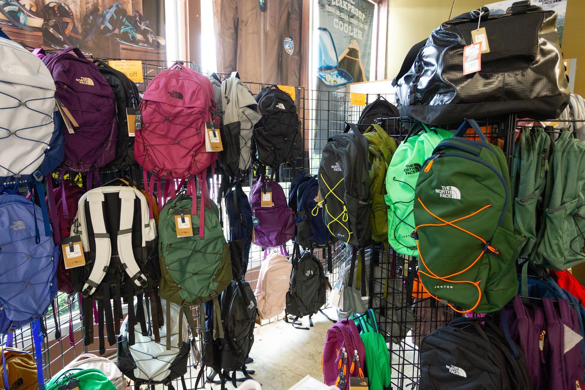 Display of The North Face backpacks in various colors at a retail store. Backpacks are on racks with price tags.